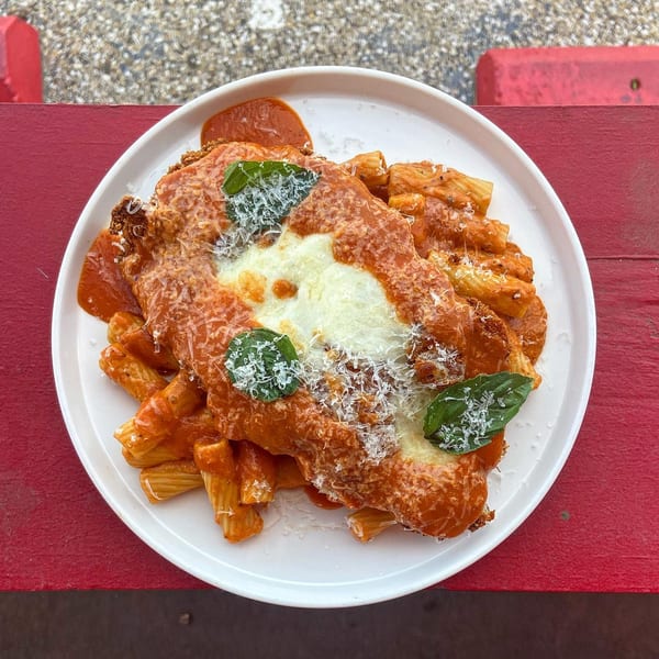 Picone's rigatoni pasta with red sauce, melted mozzarella, grated cheese, and fresh basil on a white plate.