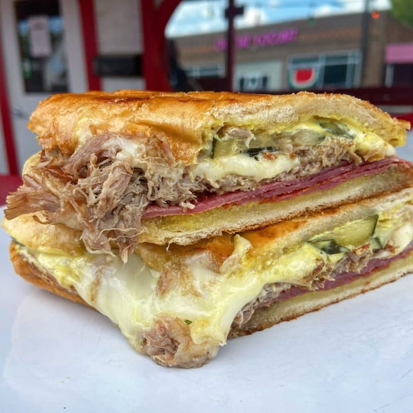 Close-up of a Cuban sandwich from Picone, with pulled pork, ham, cheese, and pickles.
